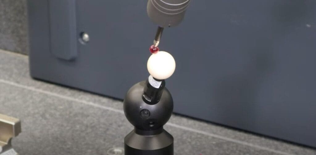 cmm calibration scanning a sphere with red tipped probe. 